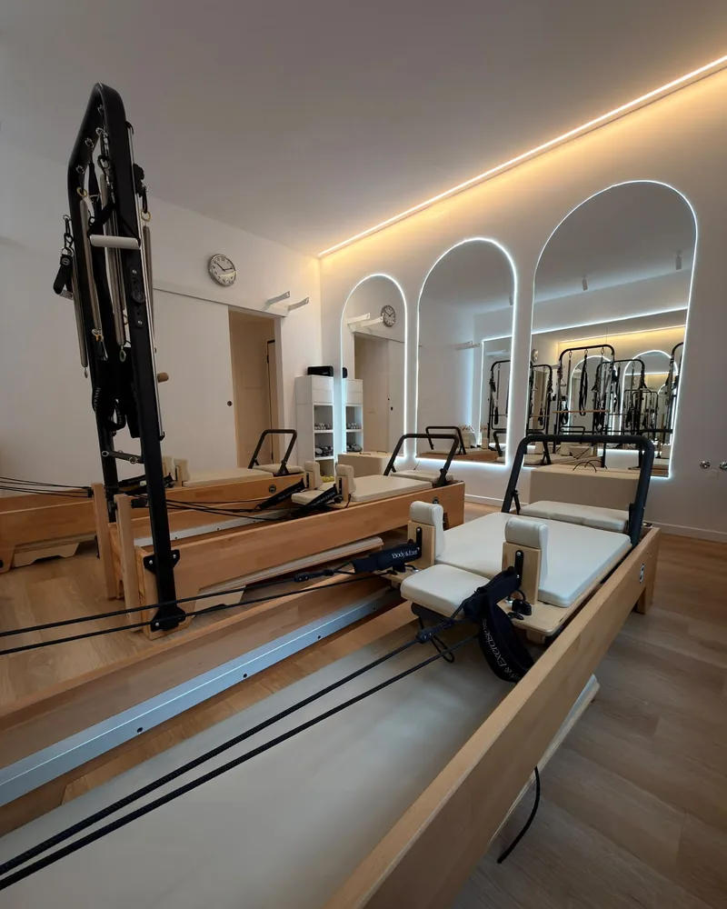 Sala dello studio con i reformer e i grandi specchi ad arco, illuminata da una luce calda